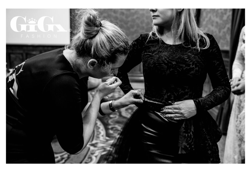 A Giga Fashion designer assisting a client during a dress fitting, ensuring the perfect fit and final adjustments.